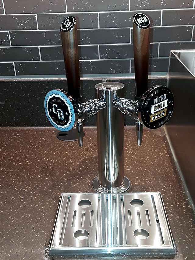 A stainless Nitro Cold Brew tap tower with two taps and a drip tray, installed on a counter