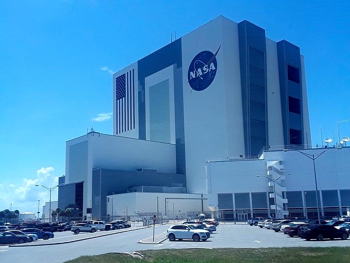 The Vehicle Assembly Building with the NASA logo and a giant American flag on its side