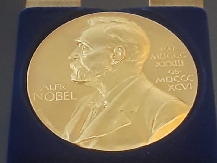 A gold Nobel Prize medal on display in a blue velvet case
