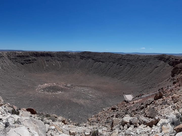 The wide bowl of Meteor Crater seen from its rim, with a viewing platform on the far side