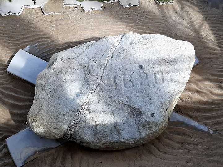 Plymouth Rock, carved with the year 1620, resting on rippled sand