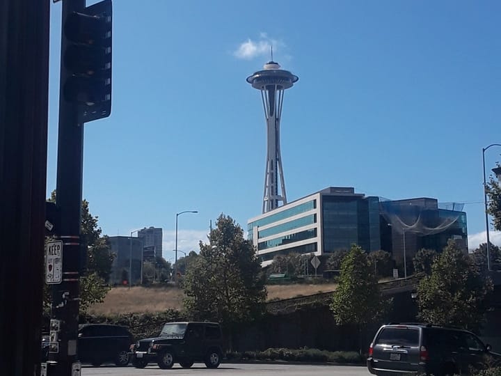 The Space Needle rising over a street corner
