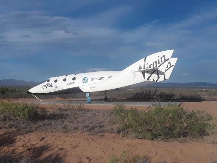 A white Virgin Galactic spaceplane parked in the desert under a deep blue sky