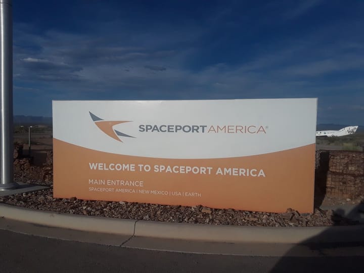 The Welcome to Spaceport America main entrance sign, with a white spaceplane just visible behind it