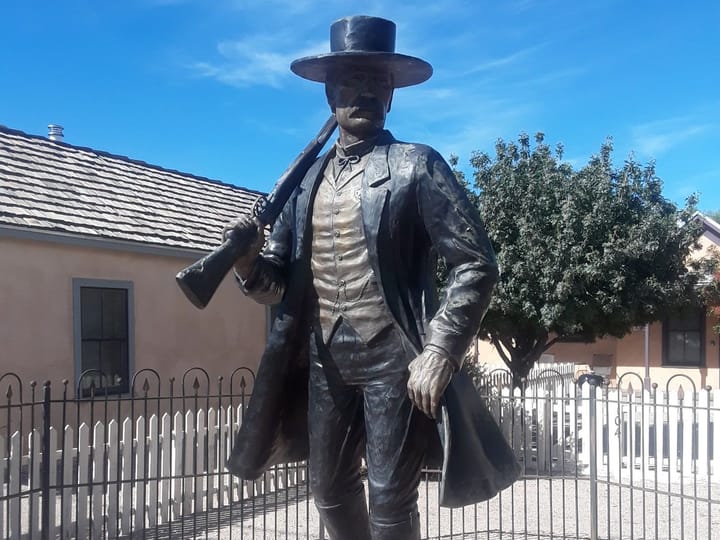 A bronze statue of a lawman with a shotgun on his shoulder